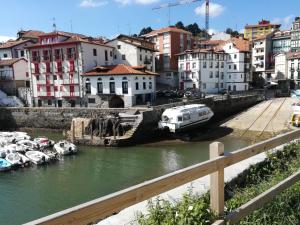 un grupo de barcos en un río con edificios en Apartamento tranquilo y luminoso en Mundaka