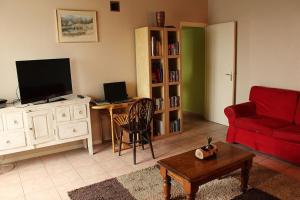 a living room with a red couch and a television at L'Aulerie in Saint-Méard-de-Gurçon