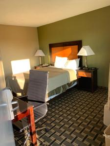 a hotel room with a bed and a desk and a chair at Relax Inn Heth in Shell Lake