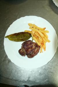 a plate of food with a pickle and french fries at Bungalows Camping Parque Nacional de Monfragüe in Malpartida de Plasencia