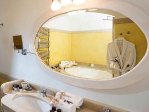 a bathroom with a tub and a sink and a mirror at Borgobianco Resort & Spa Polignano - MGallery Collection in Polignano a Mare