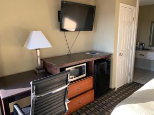 a hotel room with a desk with a tv and a chair at Relax Inn Heth in Shell Lake