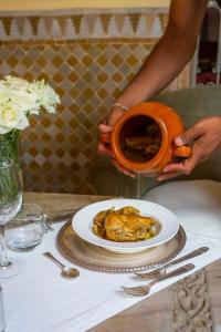 a person holding a pot with a plate of food at Riad Azoulay in Marrakesh