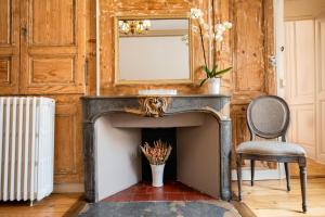 a fireplace in a room with a mirror and a chair at L'Aristoloche in Salins-les-Bains