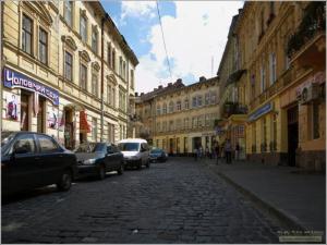 a city street with cars parked on a cobblestone street at Апартаменти для пари в центральній частині Львова in Lviv