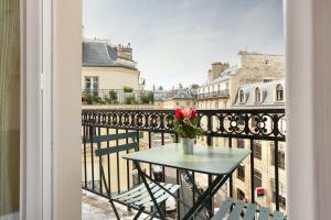 einen Tisch mit einer Blumenvase auf dem Balkon in der Unterkunft Hotel du College de France in Paris