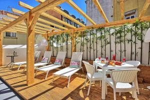 a wooden pergola with white tables and chairs on a patio at Localtraveling Cathedral & Castle - Family Apartments in Lisbon