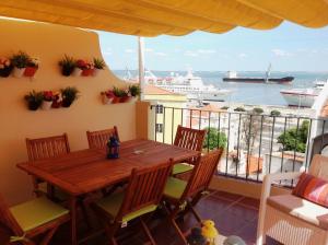 a balcony with a wooden table and chairs and a cruise ship at Localtraveling Remedios in Lisbon