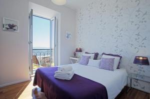 a white bedroom with a large bed with purple sheets at Localtraveling Remedios in Lisbon