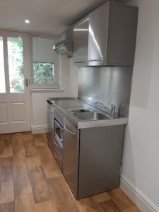 a stainless steel kitchen with a sink and a door at The Rectory Rooms, Studio 4 in Skipton