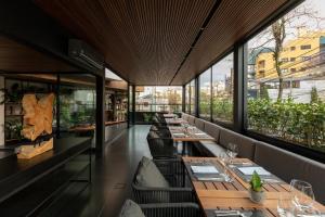 un restaurante con mesas largas, sillas y ventanas en Nomaa Hotel en Curitiba