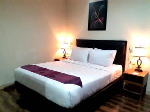 a bedroom with a large bed with two lamps at Pacific Hotel Ambon in Ambon