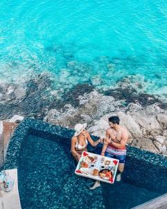 a man and woman holding a tray of food in the water at Cocobay Resort Antigua - All Inclusive - Adults Only in Johnsons Point