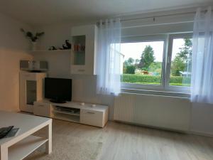 ein Wohnzimmer mit einem TV und einem großen Fenster in der Unterkunft Moderne helle 2,5 Zimmer Wohnung mit großem Bad und Küche in Trossingen in Trossingen