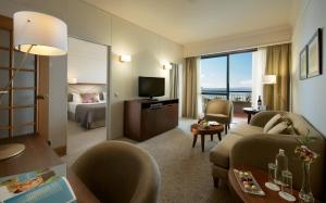 a hotel room with a couch and a television at The Cliff Bay - PortoBay in Funchal