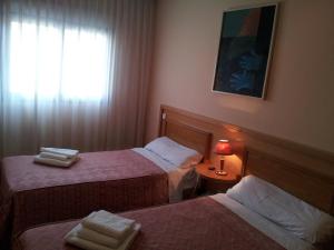 a hotel room with two beds and a window at Hostal Juan XXIII in San Sebastián de los Reyes