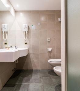 a bathroom with a toilet, sink, and mirror at Garni Aritz in Campitello di Fassa