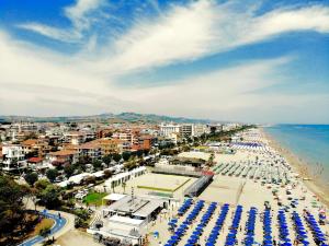 una spiaggia con un mucchio di ombrelloni e l'oceano di Hotel La Pergola ad Alba Adriatica