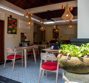 a restaurant with wooden tables and red chairs and lights at Ratna Villa 4 in Ubud