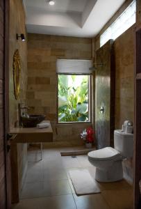 een badkamer met een wastafel, een toilet en een raam bij Ratna Villa 4 in Ubud