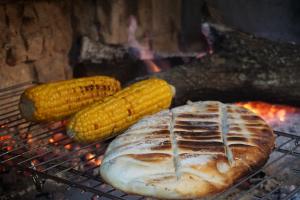 a chicken and corn cooking on a grill at Finca Las Margaritas in Chicoana