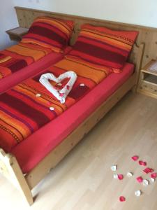 a bed with a red and orange blanket and some pills at Logis de la Licorne in La Ferrière