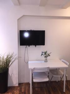 a white table with two chairs and a tv on a wall at Central sweet BNB in Amsterdam