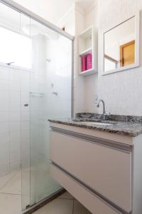 uma casa de banho branca com um lavatório e um chuveiro em Spot Residence São Carlos 700m da USP em São Carlos
