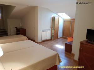 a hotel room with two beds and a television at Hotel Meleiros in Castro de Sanabria