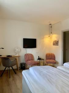 a bedroom with a bed and two chairs and a desk at Hotel Schaumburg in Holstebro