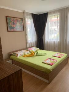 a bedroom with a bed with green sheets and a window at Jacky's Apartament - Апартамент в Свети Влас in Sveti Vlas