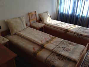a room with two beds and a chair and a window at Katya Guest House in Smolyan