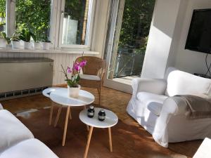 een woonkamer met witte meubels en 2 tafels bij KernerApartement in Stuttgart