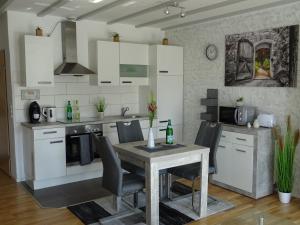 a kitchen with white cabinets and a table with chairs at Gäste Domizil Edel Zeit in Allenbach