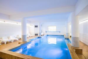 una gran piscina en una habitación con columnas blancas en SOWELL Family Valfrejus, en Valfréjus