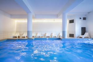 - une piscine d'eau dans une pièce avec des chaises blanches dans l'établissement SOWELL Family Valfrejus, à Valfréjus