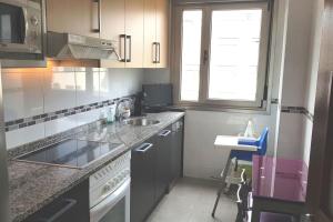 a kitchen with a sink and a counter top at Lauredal - Ático con amplia terraza, 2 hab, 2 baños, pádel, parque infantil in Gijón