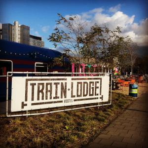 a sign that reads train lodge on a fence at Train Lodge Amsterdam in Amsterdam
