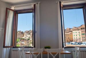 een tafel en stoelen in een kamer met ramen bij Casa in Contrada in Siena