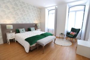 a bedroom with a large bed and a chair at Glass Boutique - Rooms & Suites in Marinha Grande