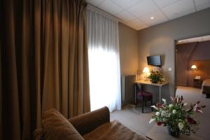 - un salon avec un canapé et une chambre avec un bureau dans l'établissement Hôtel CAP VERT en Aveyron, à Saint-Affrique