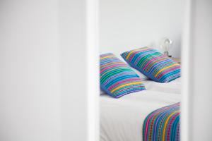 a white bed with two colorful pillows on it at Cocor Suites & Design in Naples