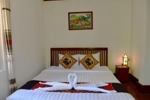 a bedroom with a bed with white towels on it at Thatsaphone Hotel in Luang Prabang