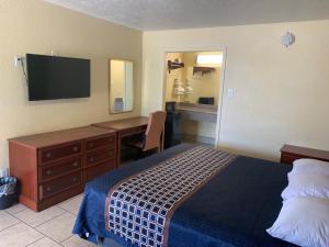 a hotel room with a bed and a desk and a television at Texas Inn Beaumont in Beaumont