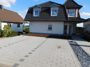 a white house with a black roof and a driveway at Ferienwohnung Elsbeere in Blankenheim