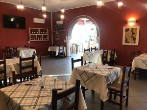 un restaurante con mesas y sillas blancas y una pared roja en Albergo Antica Luni en Luni