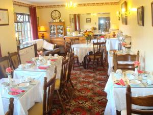 - une salle à manger avec des tables, des chaises et du linge de maison blanc dans l'établissement Athlumney Manor Guest Accommodation, à Navan