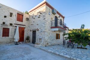 un bâtiment avec un balcon, une table et un parasol dans l'établissement Villa Tzaniana, à Apomarmá