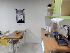 a kitchen with a sink and a table with chairs at Studio Jolie in Novi Sad