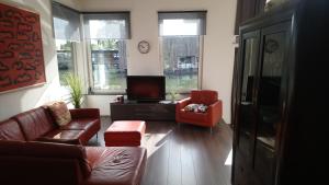 a living room with a couch and two chairs and a tv at Houseboat Vliegenbos in Amsterdam